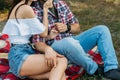 sexual attraction. a guy and a girl are sitting on a plaid veil on the grass, hugging and kissing. a man in a plaid shirt and jean Royalty Free Stock Photo