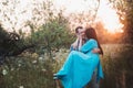 The guy and the girl standing on nature, embrace and kiss under the guise of a wide hat