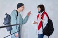 Guy and girl, teenage students with backpacks, standing talking indoors Royalty Free Stock Photo