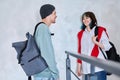 Guy and girl, teenage students with backpacks, standing talking indoors Royalty Free Stock Photo