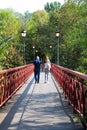 A guy and a girl walk holding hands with their backs turned on a pedestrian bridge with red railings Royalty Free Stock Photo