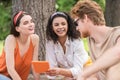 Guy and girls with tablet communicating at picnic Royalty Free Stock Photo