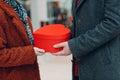 A guy give his girlfriend a heart-shaped box in Valentine& x27;s Day. Young couple at shopping mall.