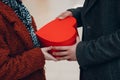 A guy gives his girlfriend a heart-shaped box close up in Valentine& x27;s Day. Young couple at shopping mall.