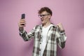 guy with glasses holds smartphone and shows celebrating the victory, winner with the phone shows success