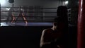 Guy in gloves beats a pear, in the background in the ring there is a sparring of kickboxers. Slow motion