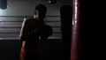 Guy in gloves beats a pear, in the background in the ring there is a sparring of kickboxers. Slow motion