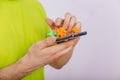 A guy in a green T-shirt is holding a smartphone with a coronavirus on the screen. Dirty phone. Personal hygiene