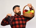 Guy with harvest. Farmer with serious face presents apples, cranberries and grapes.