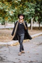 A guy in a hat and coat goes down the street. Outdoors. Royalty Free Stock Photo