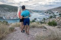A guy and his girlfriend are standing on the edge of a cliff hugging each other by the waist and admiring Balaklava Bay in Crimea