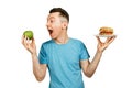 Guy hold green apple and a hamburger on light background. Concept of choosing between healthy and unhealthy fast food Royalty Free Stock Photo