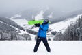 The guy hold on the shoulder green snowboard in winter