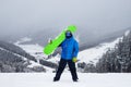 The guy hold on the shoulder green snowboard in winter