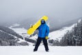 The guy hold on the shoulder yellow snowboard in winter