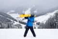 The guy hold on the shoulder yellow snowboard in winter