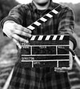 Guy is holding black clapperboard in hands. Man is directing and filming some amateur cinema movie. Rail trails on the background