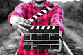 Guy is holding black clapperboard in hands. Man is directing and filming some amateur cinema movie. Rail trails on the background