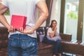 Guy holding gift behind him for surprise his waiting girlfriend at their home. Selective focus on gift Royalty Free Stock Photo