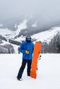 The guy holding orange snowboard next to leg in winter