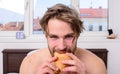 Guy holds croissant bedroom hotel room window background. Man eats croissant he likes bakery products. Guy bites sweet