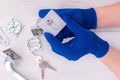 The guy holds in his hands in blue gloves the core of the lock from the door on a light background. Royalty Free Stock Photo