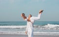 Guy holds in his hands a girl in white clothes on the ocean