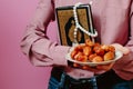 The guy holds the Holy Quran, Islamic rosary and dates. On a pink background. Royalty Free Stock Photo