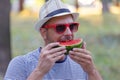 Guy holds a piece of watermelon and eating
