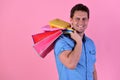 Guy holds stack of pink and yellow shopping bags