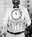 Guy holds striped present box with champagne glass and clock