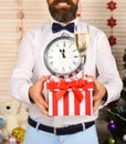 Guy holds striped present box with champagne glass and clock
