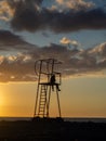 guy in a hood on a rescue tower. Silhouette of a young lonely man. Silhouette of a person looking out to sea at sunset. Royalty Free Stock Photo