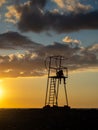 guy in a hood on a rescue tower. Silhouette of a young lonely man. Silhouette of a person looking out to sea at sunset. Royalty Free Stock Photo