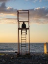 guy in a hood on a rescue tower. Silhouette of a young lonely man. Silhouette of a person looking out to sea at sunset. Royalty Free Stock Photo