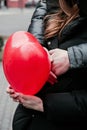 Guy hugs a beautiful young woman holding a red heart-shaped balloon, Valentine`s Day Royalty Free Stock Photo
