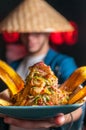 Guy in japanese disguise holding a plate of ceviche nikkei