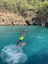 The guy jumps from the deck of the ship into the sea. A man dives into the water from a height. Swimming in the Mediterranean Sea