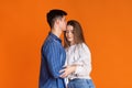 Guy kisses girl in forehead on orange background