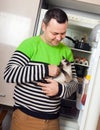 Guy with kitten near refrigerator Royalty Free Stock Photo