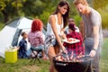 Guy and lassie putting grilled skewers on plate Royalty Free Stock Photo