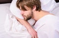 Guy lay under white bedclothes. Man unshaven handsome relaxing bed. Power napping may help you get through day. Have nap Royalty Free Stock Photo