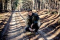 A guy in a leather jacket and cap on a road in a pine forest Royalty Free Stock Photo