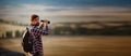 Guy looking at binoculars in hill. man in t-shirt with backpack