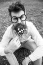 Guy looks nicely with daisy or chamomile flowers in beard. Man with long beard and mustache, defocused green background Royalty Free Stock Photo