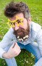 Guy looks nicely with daisy flowers in beard. Photosession concept. Man with beard and mustache, defocused green Royalty Free Stock Photo