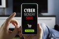 guy makes purchases through mobile app without leaving home. Convenient service. Hand Holding Mobile with the text: Cyber Monday Royalty Free Stock Photo