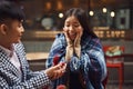 Guy makes a wedding proposal to girl sitting at table in cafe.