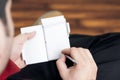 Guy making notes on a small diary while sitting relaxed in a wooden floored room