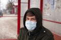 Guy in a medical mask at a bus stop.npublic coronavirus protection. virus outbreak covid-2019. viral pandemic epidemicn